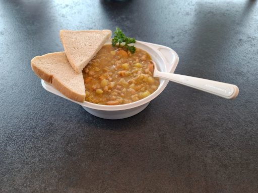 Erbsensuppe mit Einlage Linsensuppe mit zwei Brotscheiben und frischer Petersilie als Garnitur.